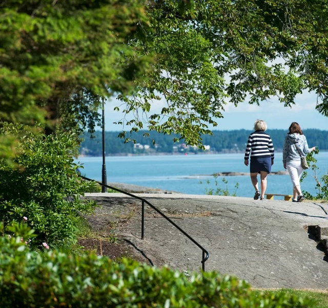 Två personer promenerar vid Vänerns vatten