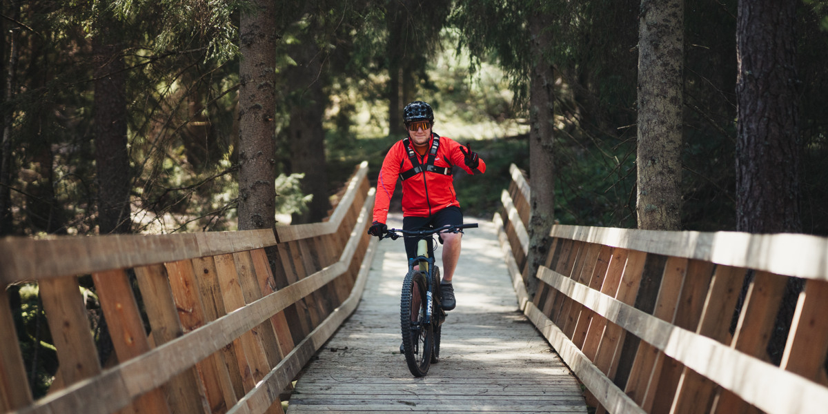 En man cyklar över en träbro.