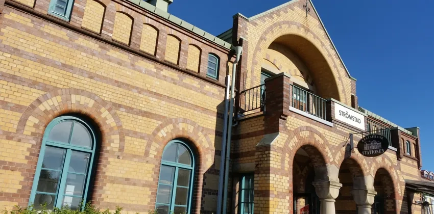Strömstad station. En tegelbyggnad med välvda fönster och en balkong.