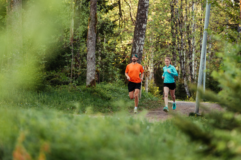 Två personer som springer längs ett motionsspår i skogen.