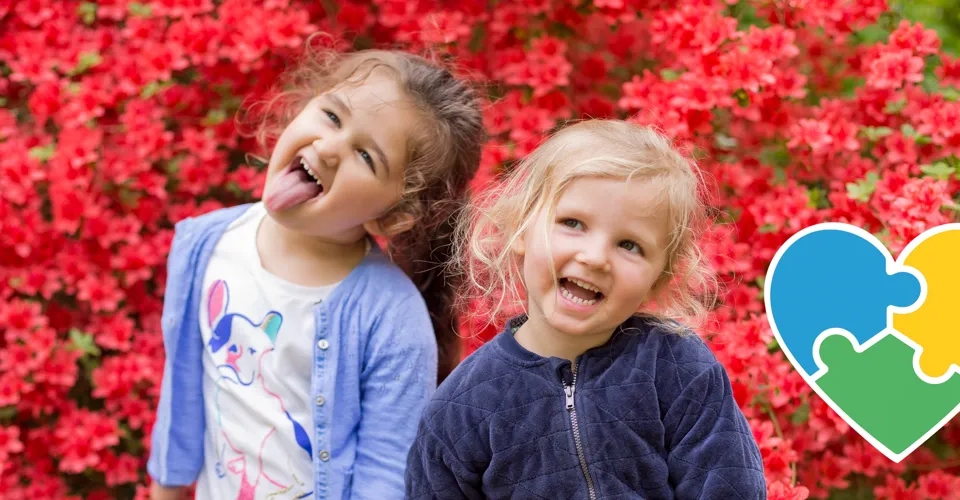 Två tjejer framför en blombuske.