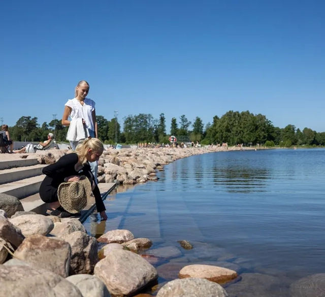 Tjej som känner på vattnet vid en badstrand.