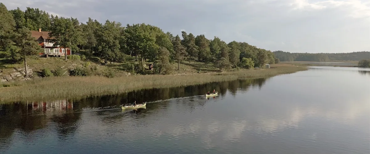Two canoes are on the water in front of a house.