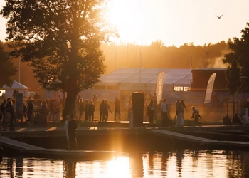 Solnedgång vid ett festivalområde med människor och tält