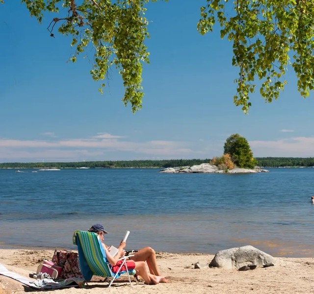 En person som sitter i en stol på en strand.