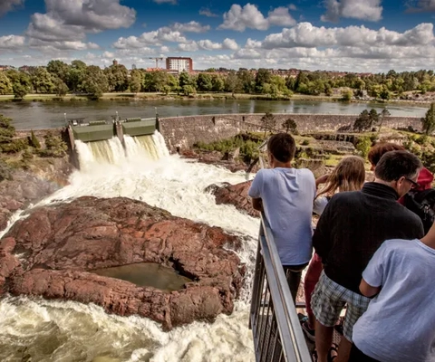 En grupp människor som står på en bro och tittar på ett vattenfall.