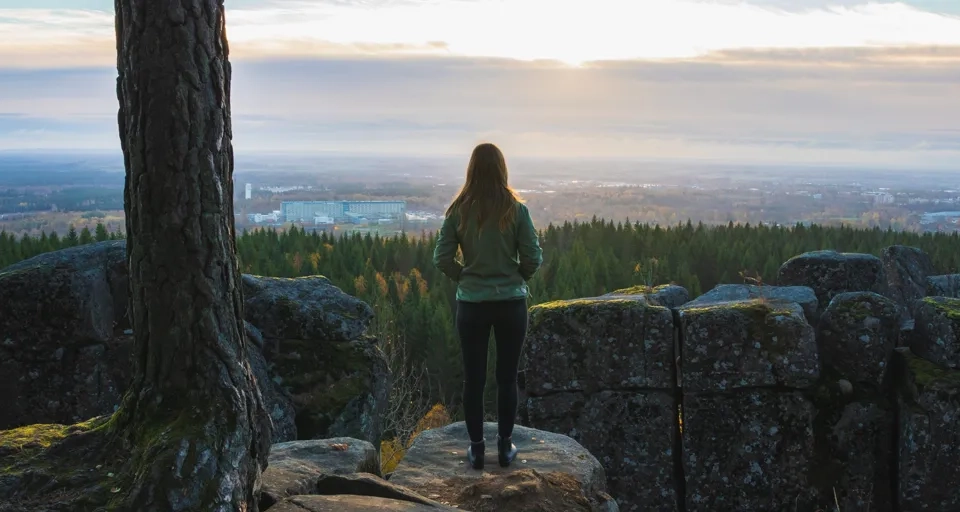 Kvinna som står med ryggen mot kameran och kikar ut över en vacker utsikt.