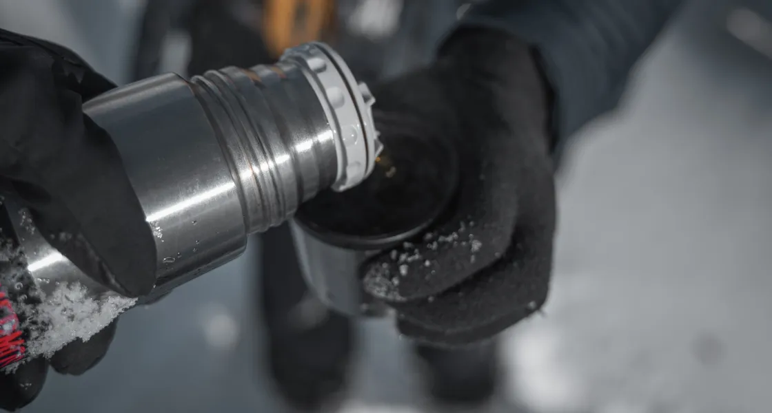 En person häller upp varmdryck i en mugg från en termos en vinterdag.