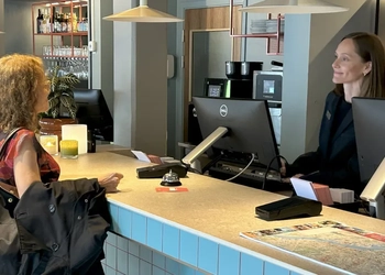 En kvinna står vid en disk och pratar med en annan kvinna.