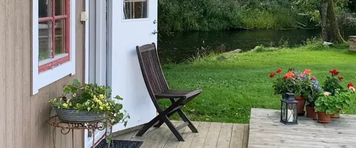 Exteriör på gaveln på ett sommarboende i sommargrönska.