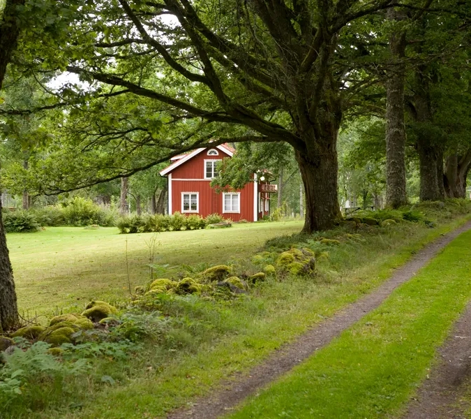 A red house sitting on the side of a lush green field.