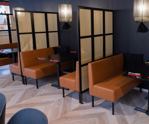 En restaurang med orangea soffor och svarta bord.