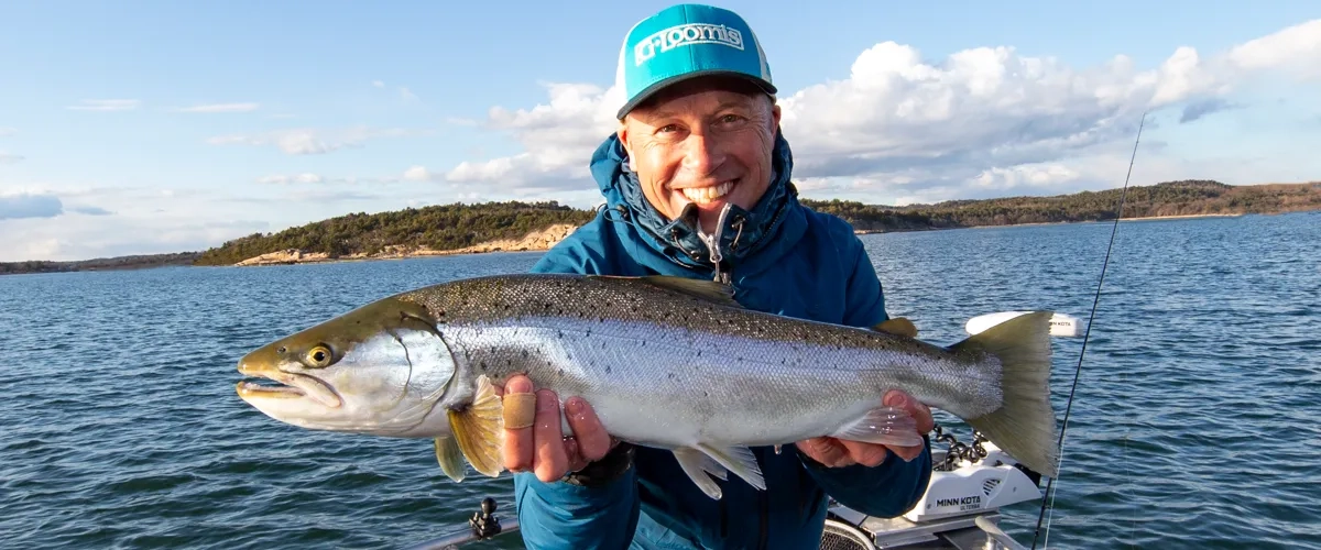 En man på en båt håller i en fisk.