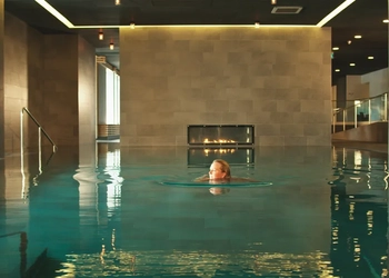 En kvinna simmar i en stor inomhuspool.