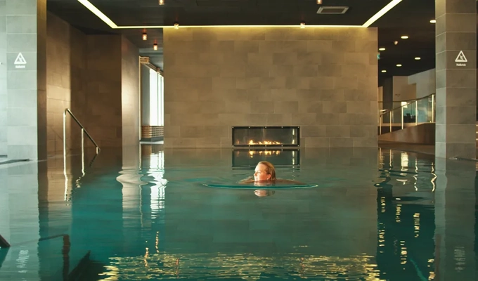 En kvinna simmar i en stor inomhuspool.