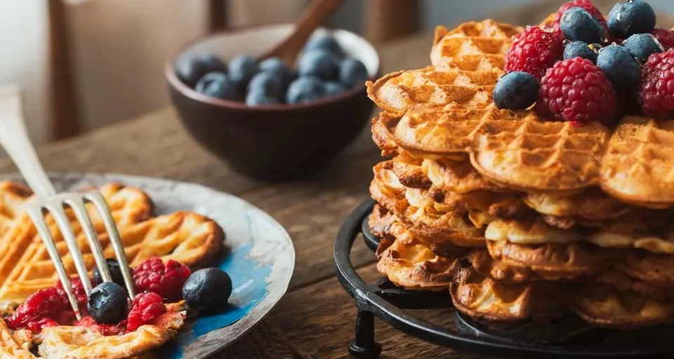 A stack of waffles topped with berries and blueberries.