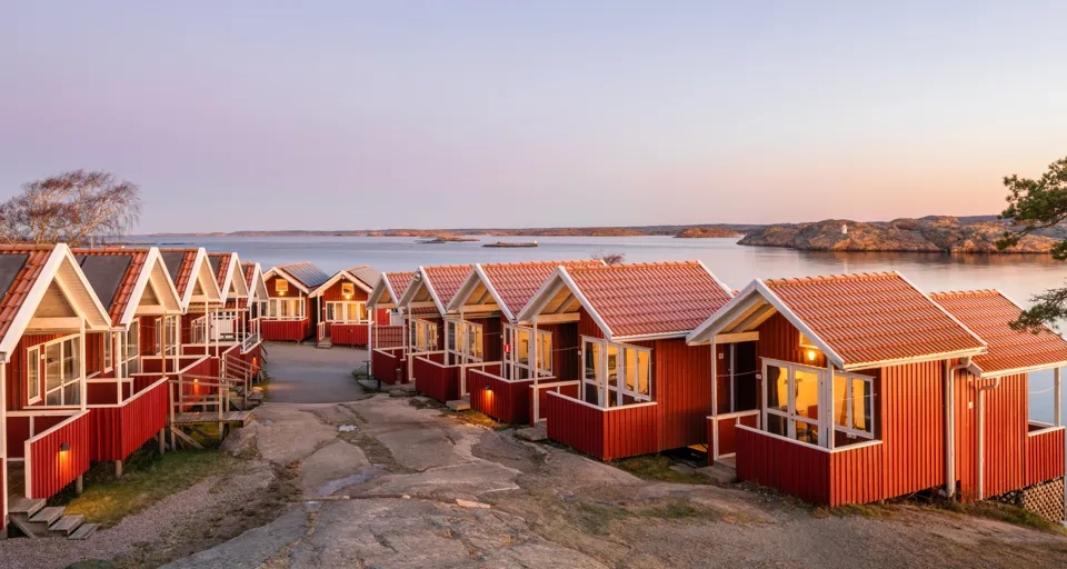 En rad röda hus som ligger intill ett vattendrag.