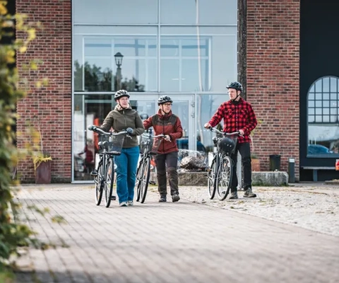 Människor som leder sina cyklar på en kullerstensgata.
