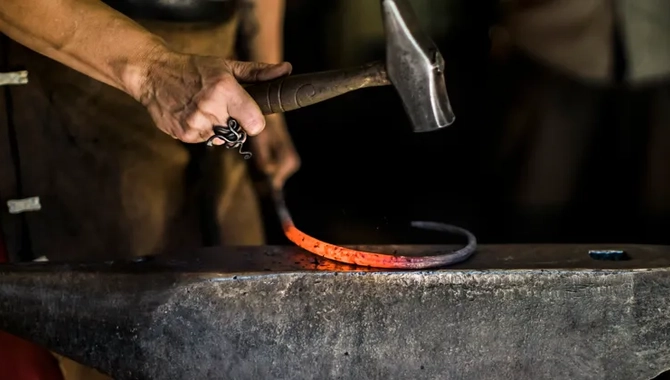 En person som håller en hammare över ett stort metallföremål.