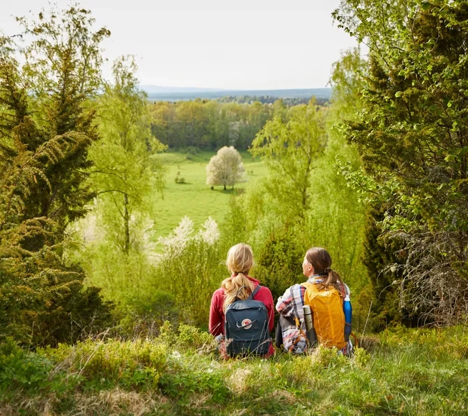 Två kvinnor som sitter på toppen av ett grönskande fält.