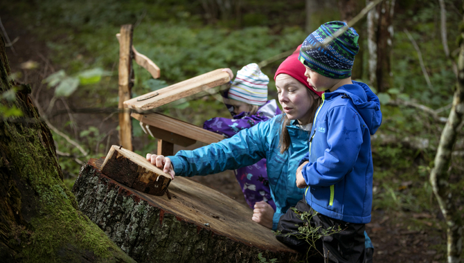 Två barn och en kvinna som står i skogen.
