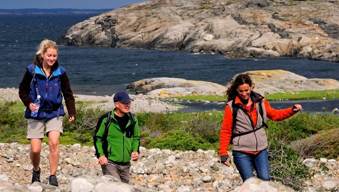 Three people hiking across a cobblestone field on North Koster.