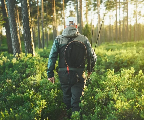 En man med ryggsäck går genom en skog.