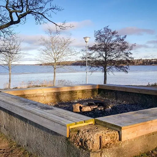 Grillplats med sittbänkar vid vattnet.