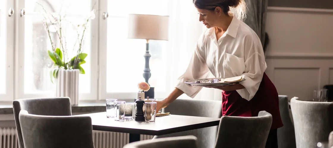 Servitris dukar av ett bord på en restaurang