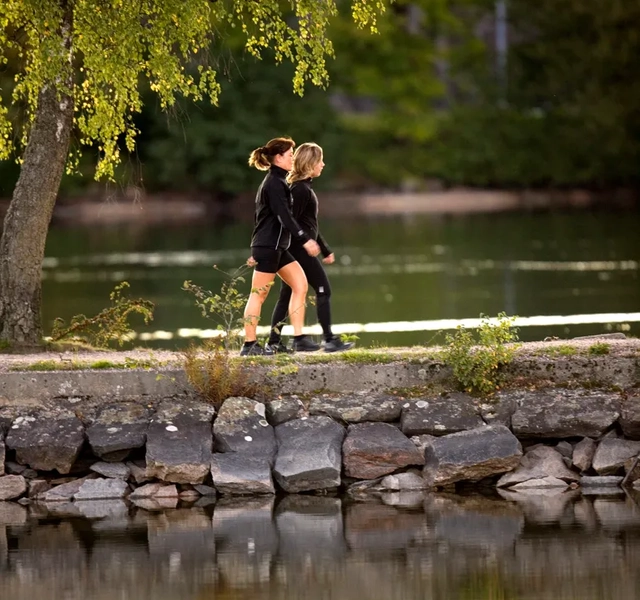 Två personer som promenerar längs vattnet