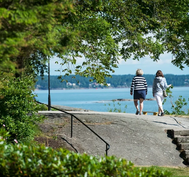 Två personer promenerar vid Vänerns vatten