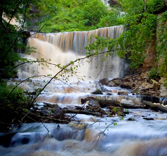 Ett vattenfall med vatten som rinner ner omgivet av träd.