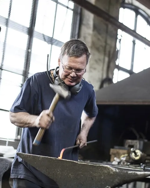 En man arbetar med ett metallstycke.