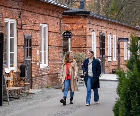 Två kvinnor går i en gammal bruksmiljö.