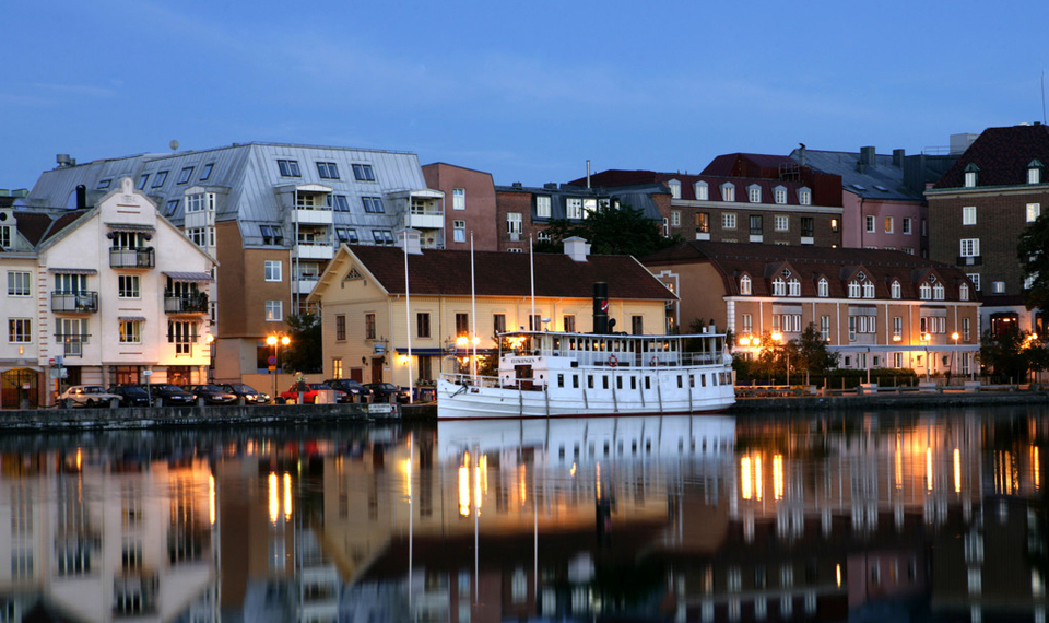 En båt ligger i vattnet framför några byggnader.