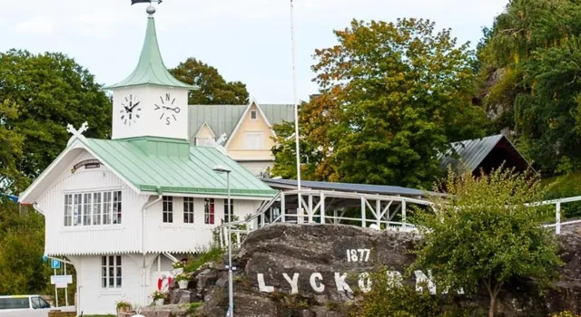 En vit byggnad med ett grönt tak intill ett vattendrag.