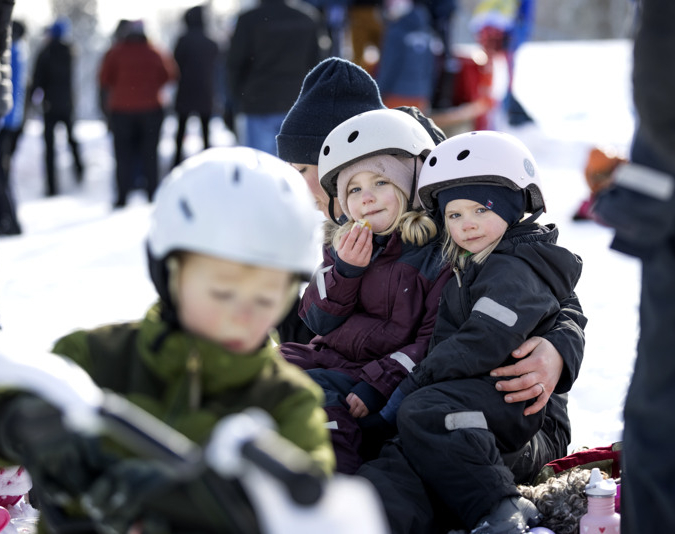 En grupp små barn sitter på en snötäckt mark.