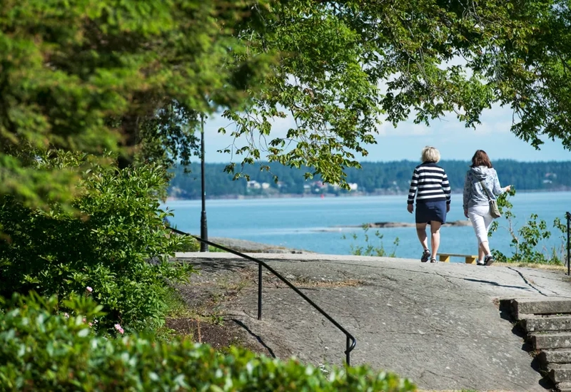 Två personer promenerar vid Vänerns vatten