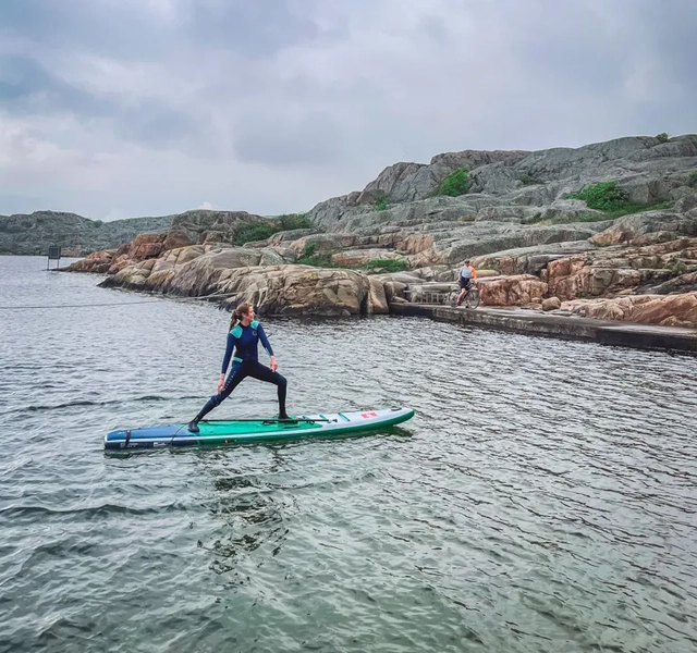 En person som står på en surfbräda i vattnet.