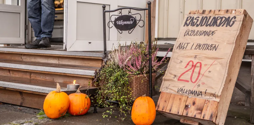 Pumpkins and a sign on the steps of a house.