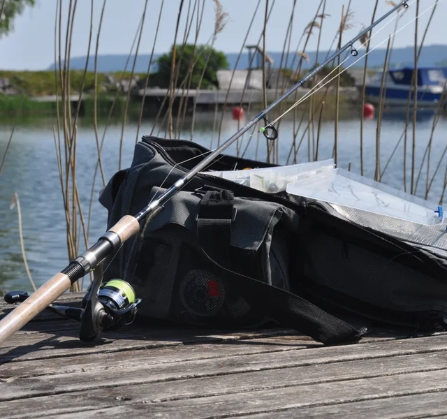 väska med redskap och fiskespö på brygga