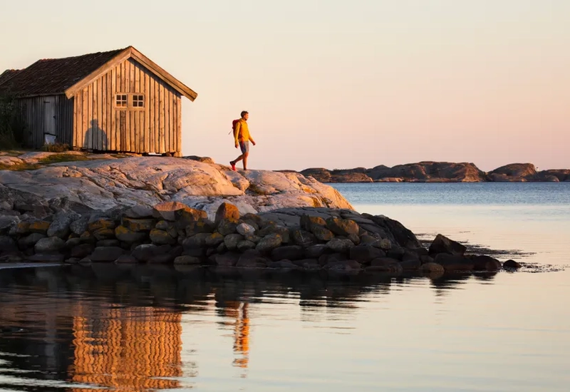 A man standing on top of a rock next to a body of water.