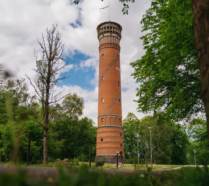 Utsiktstorn i rött tegel med träd och buskar runt omkring.