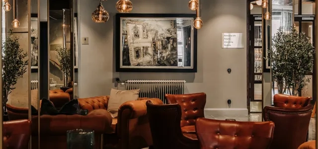 Foajé med fåtöljer, bord och dov belysning.