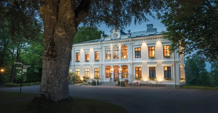 En stor vit byggnad som sitter bredvid ett träd.