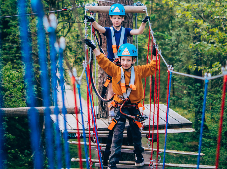 Two boys riding on top of a zip line.