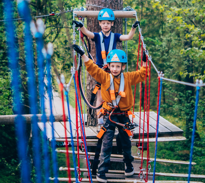 Two boys riding on top of a zip line.