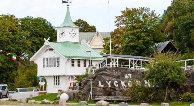 En vit byggnad med ett grönt tak intill ett vattendrag.