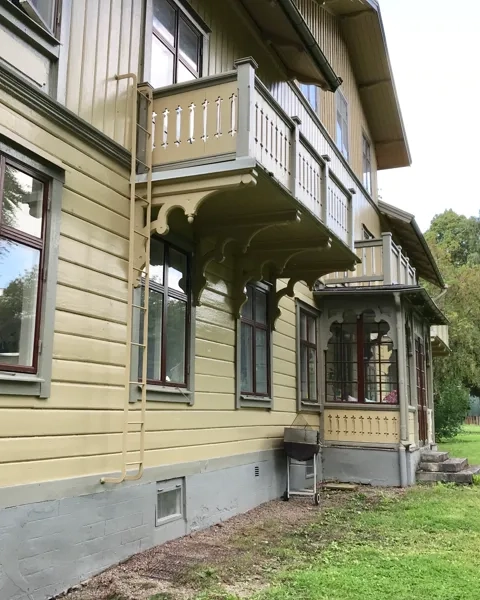 Gul stor träbyggnad med veranda.