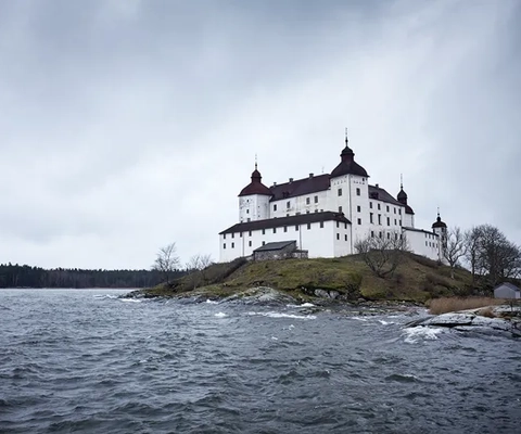 Ett stort vitt slott som ligger på toppen av en liten ö.